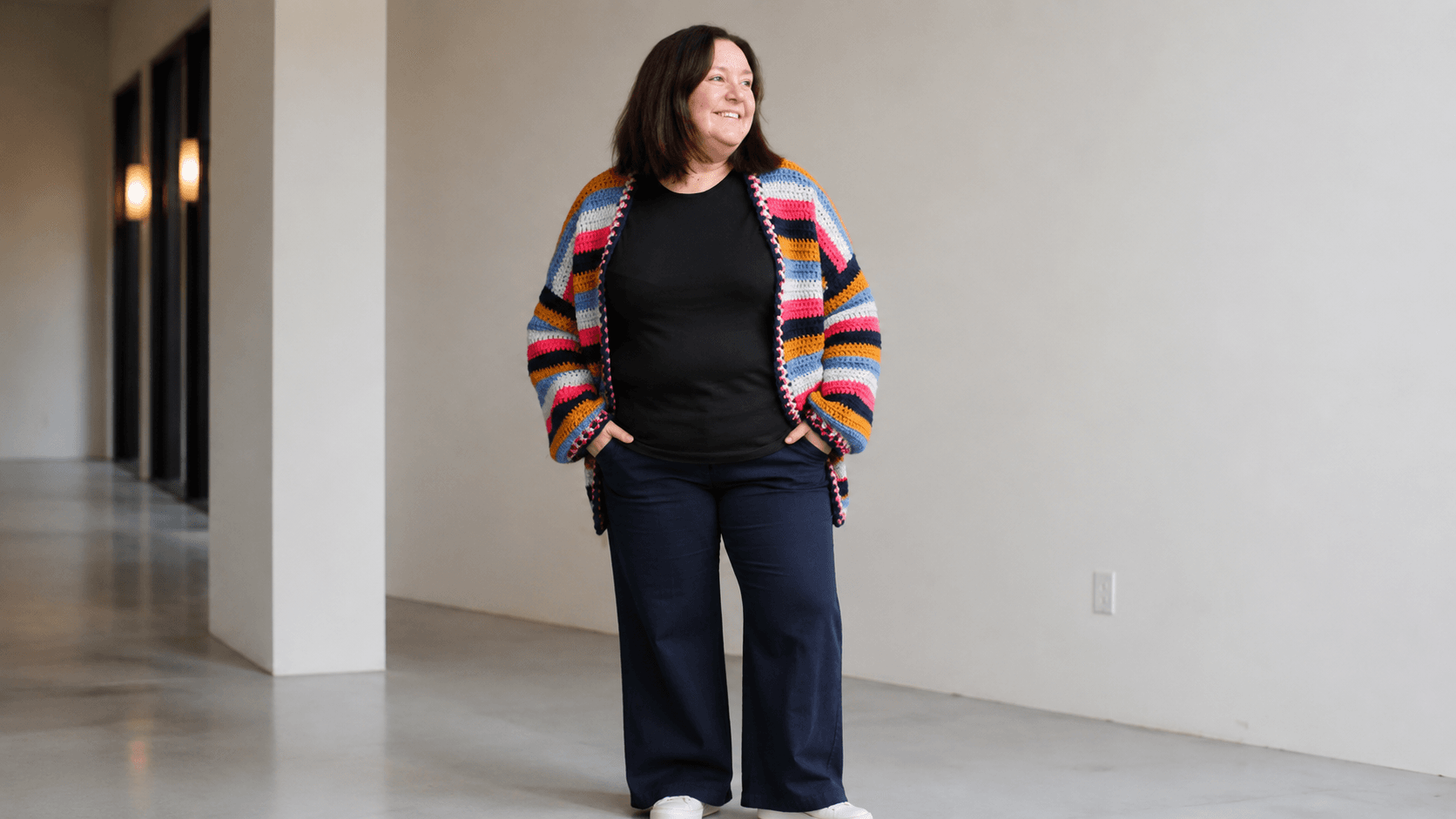 Woman wearing a mustard, pink, navy, and blue striped crochet cardigan