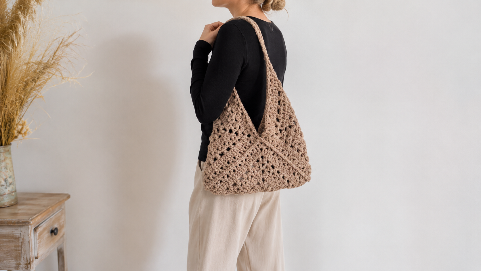 Tan triangular crochet bag worn on the back, made from folded granny squares