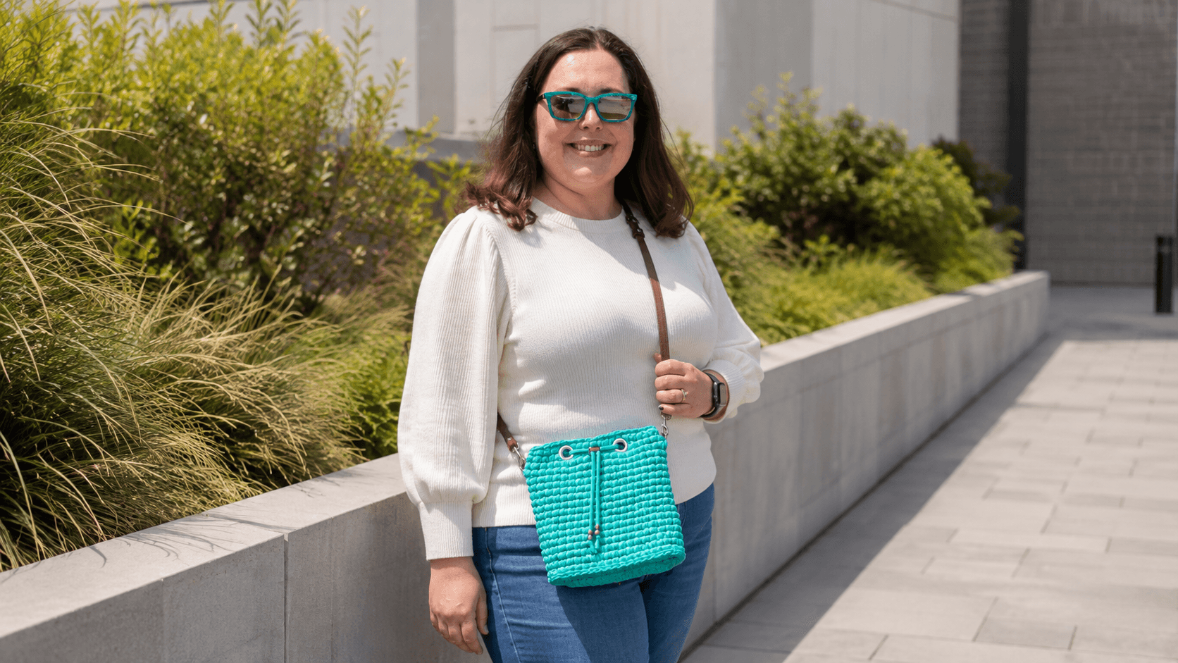 Woman wearing a teal crochet drawstring crossbody bag