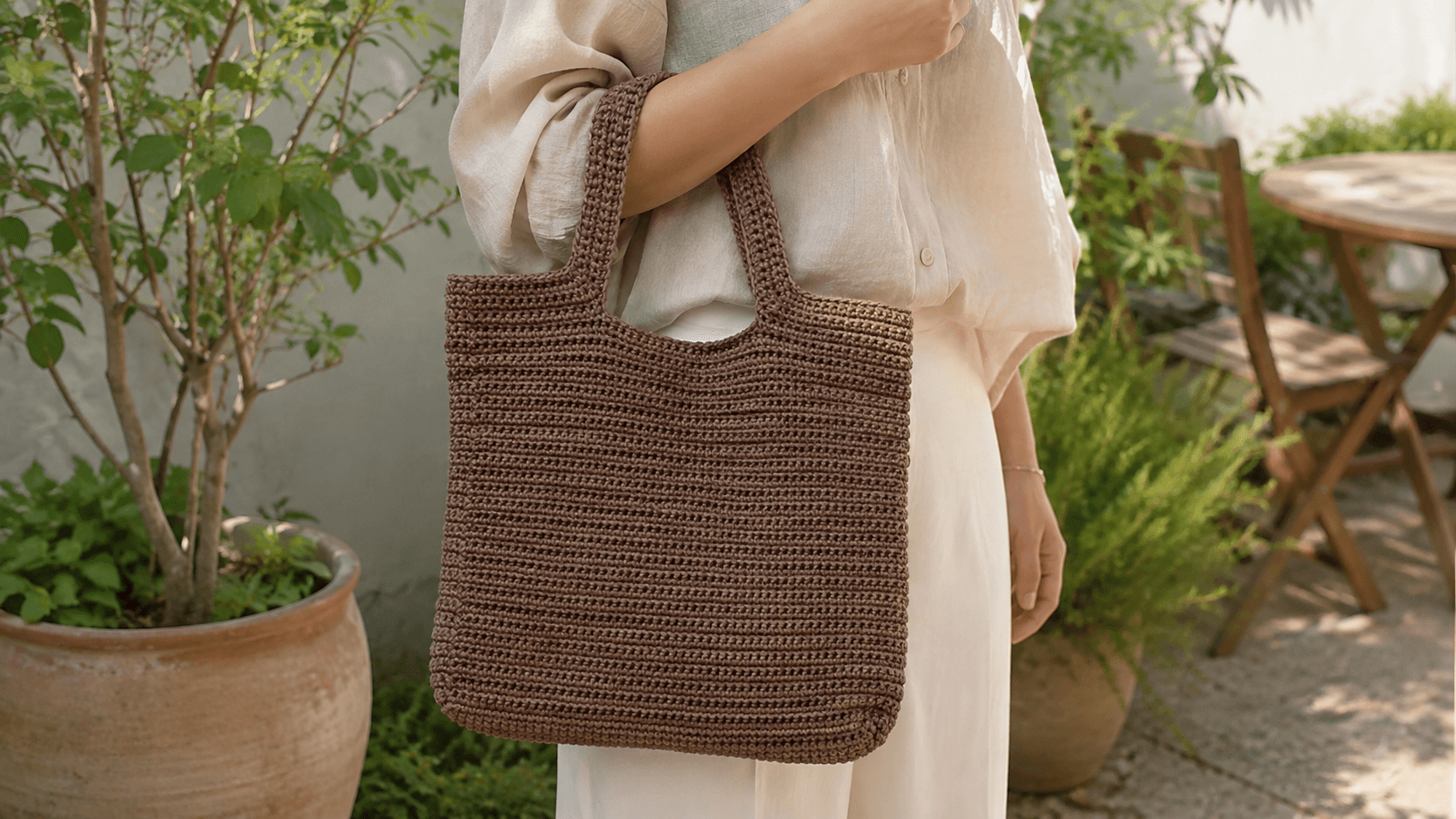 Mocha brown crochet tote bag held near a window