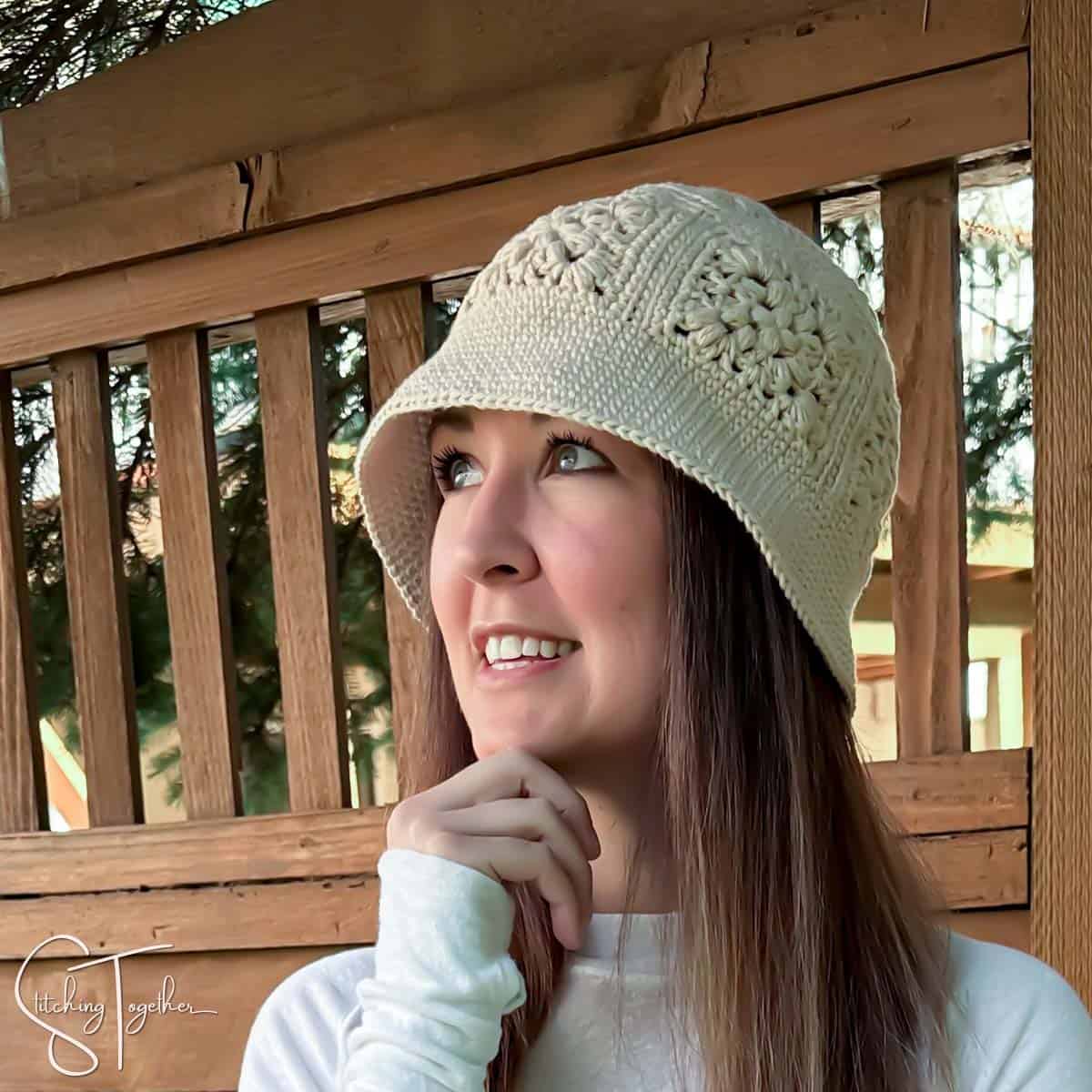 Woman wearing a cream crochet bucket hat with puff stitch granny square details