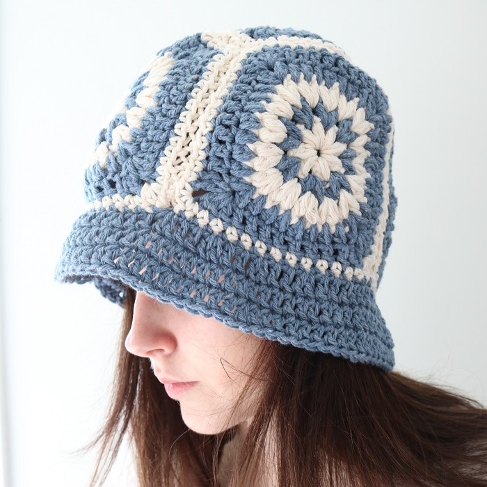 Woman wearing a slate blue and cream granny square crochet bucket hat