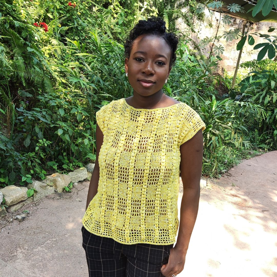 Woman wearing a yellow crochet lace top with a leaf stitch pattern