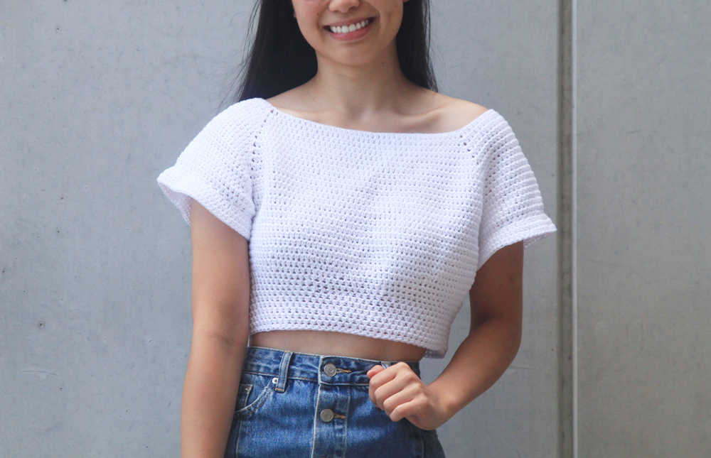 Woman wearing a white off-shoulder crochet crop top with denim jeans
